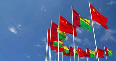 Guinea Bissau and China Flags Waving Together in the Sky, Seamless Loop in Wind, Space on Left Side for Design or Information, 3D Rendering video