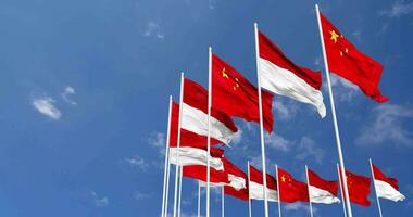 Indonesia e Cina bandiere agitando insieme nel il cielo, senza soluzione di continuità ciclo continuo nel vento, spazio su sinistra lato per design o informazione, 3d interpretazione video