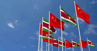 Suriname and China Flags Waving Together in the Sky, Seamless Loop in Wind, Space on Left Side for Design or Information, 3D Rendering video