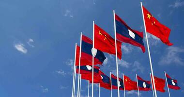 Laos et Chine drapeaux agitant ensemble dans le ciel, sans couture boucle dans vent, espace sur la gauche côté pour conception ou information, 3d le rendu video