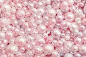 Beautiful background pink pearl pearls, top view. Abstract texture for festive backgrounds. Shiny surface of Christmas decorations. Gems close-up. Multicolored bright background. photo