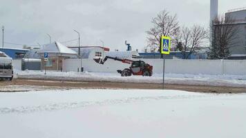 Aufnahmen von das Traktor Reinigung oben das Straße während Schneefall. Jahreszeit video