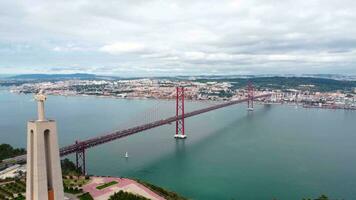 aéreo perspectiva do santuário de cristo rei estátua e 25 abril ponte. a estátua é situado dentro almeda e a ponte conectar a Lisboa cidade com Almada. video