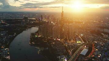 antenne zonsondergang visie Bij mijlpaal 81 - het is een super hoog wolkenkrabber en Saigon brug met ontwikkeling gebouwen langs Saigon rivier- licht glad naar beneden video