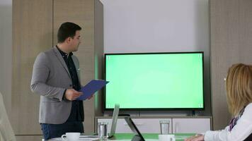 homme d'affaire avec une presse-papiers dans mains dans de face de la télé avec vert écran chrominance moquer en haut video