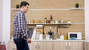 Happy woman jumps in man arms in the kitchen. He catches her and they laugh and smile. Slow motion footage video