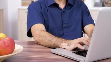 Male hands typing on computer keyboard in the kitchen. Dolly slider 4K footage video