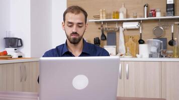 joven hombre trabajando a el ordenador portátil computadora en el cocina. muñequita control deslizante 4k imágenes video