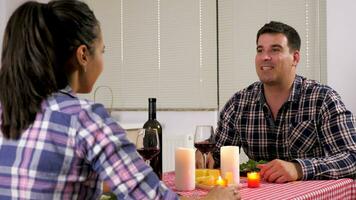 Pareja teniendo un romántico cena a hogar en el cocina a el vela luces. ellos bebida vino y comer queso y ensalada. muñequita control deslizante 4k imágenes video