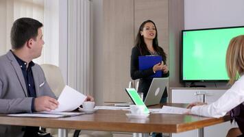 Revealing shot of beautiful businesswoman in front of green screen mock-up chroma TV with a clipboard in hands video