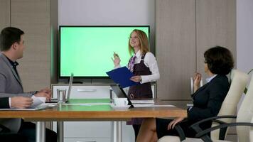 femme d'affaires dans conférence pièce dans de face de gros écran la télé avec vert écran chrominance maquette. chariot glissière 4k métrage video