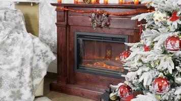 Christmas tree near a beautiful fireplace. Garlands are one and the fire is burning. Static shot video