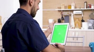 Man holding a digital tablet PC in vertical mode looking at green screen chroma mock up video