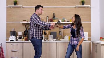 Happy laughing couple fighting with big spoons in the kitchen. Slow motion footage video