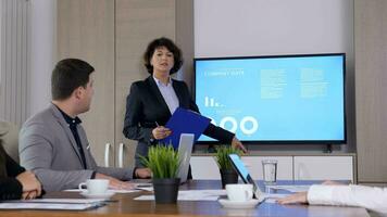 Businesswoman presents animated charts to colleagues in meeting room. Dolly slider 4K footage video