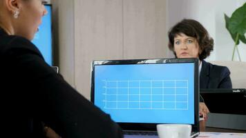 Laptop with data analysis in front of business woman in the conference room. She looks at the display while talking with her colleagues. Dolly slider 4K footage video