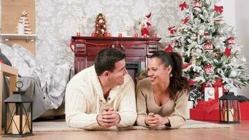 Couple on the floor laughing and having a good time in Christmas eve. There is a fireplace in the background video