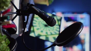 Vertical video Close up shot of podcast microphone used to record conversations for internet livestreaming show. Streaming sound capturing and recording technology in empty home studio with neon lights