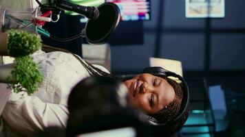 Vertical video African american host engaging in entertaining discussion with celebrity during live stream in professional studio, making her laugh. Presenter uses high quality equipment to produce comedy podcast