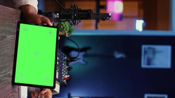 Vertical video Woman and man participating in podcast, laughing while watching funny internet clips on green screen tablet in studio, discussing content. Podcasters reacting to amusing videos on chroma key device