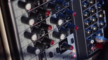 Vertical video Close up shot of professional analog mixer with mixing channels, onboard effects and quality microphone able to produce impeccable sound during podcast recording in dimly lit studio