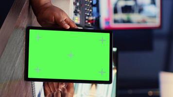 Vertical video Green screen tablet hold by woman on podcast discussing with guest during marathon stream for humanitarian cause. Chroma key device used by host to check gathered donations from audience during show