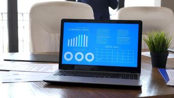 Computer on a table in conference room displaying animated data and charts video