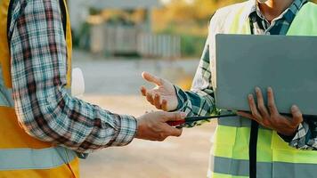 diverso equipe do especialistas usar computador portátil computador em construção local. real Estado construção projeto com Civil engenheiro, arquitetônico investidor, empresária e trabalhador discutindo plano detalhes video