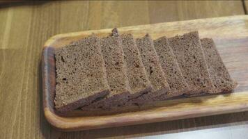 Cut slices of black bread lie on wooden rectangular plate. video