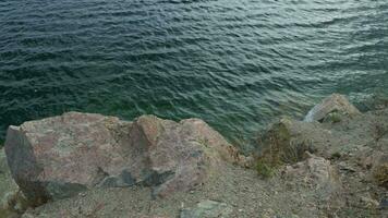 View from cliff onto calm water surface with small ripples. video