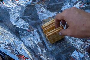 Man hold the crispy cracker biscuit over the aluminum cover. photo