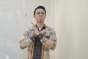 Young Indonesian wear batik traditional culture of Indonesia with rejected gesture. photo