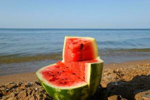 The cut watermelon lies on the seashore. Watermelon in the sea photo