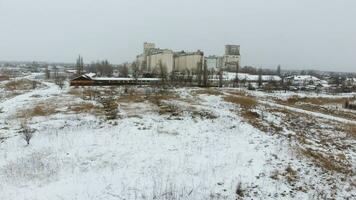 Grain terminal in the winter season. Snow-covered grain elevator in rural areas. A building for drying and storing grain. photo