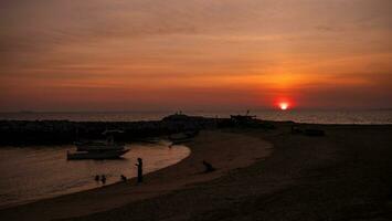 Sunset on the bay with small fishing boats couple of people on the beach photo