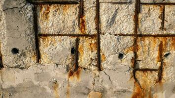 An old concrete wall with rust showing the structure inside. photo