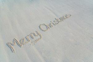 Merry Christmas beach text handwritten in sand on a beach background photo
