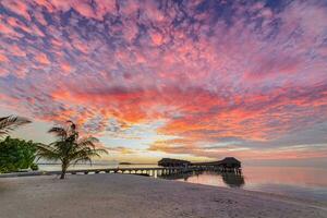 Amazing beach landscape. Beautiful Maldives sunset seascape view. Horizon colorful sea sky clouds, over water villa pier pathway. Tranquil island lagoon, tourism travel background. Exotic vacation photo