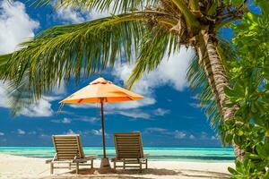 Beautiful tropical island scenery, two sun beds, loungers, umbrella under palm tree. White sand, sea view with horizon, idyllic blue sky, calmness and relaxation. Inspirational beach resort hotel photo