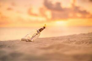 Message in the bottle washed ashore against the sun setting down. Tropical beach sea shore castaway design background photo