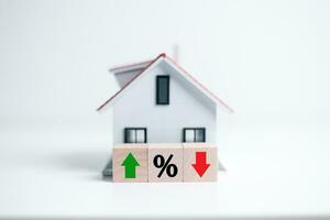 Resident rate, real estate, property and building annual taxation. percentage icon with house model and up and down arrow on wood block. House and property investment and asset management concept. photo