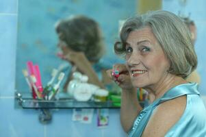 Portrait of beautiful old woman doing makeup photo