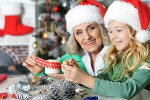 Grandmother and granddaughter in Santa hats making New Year's decorations photo