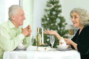 Elderly couple at the dinner table giving a New Year's gift photo