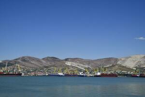 carga Puerto con Puerto grúas mar bahía y montañoso costa. foto