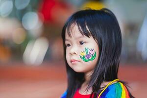 Cute kid girl cheeks are painted with flowers at Easter event. Empty space for entering text. photo