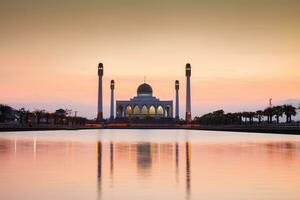 silhouette mosque reflection on water at sunset photo