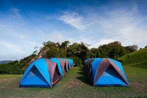 Camping tent on green grass againts sky photo
