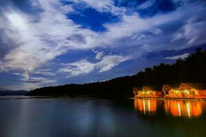 hut reflection on water in dam at night time photo