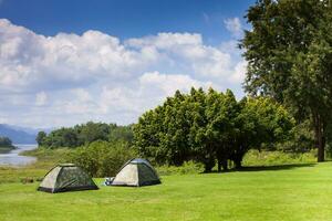 Camping tent on green grass field under clear sky photo